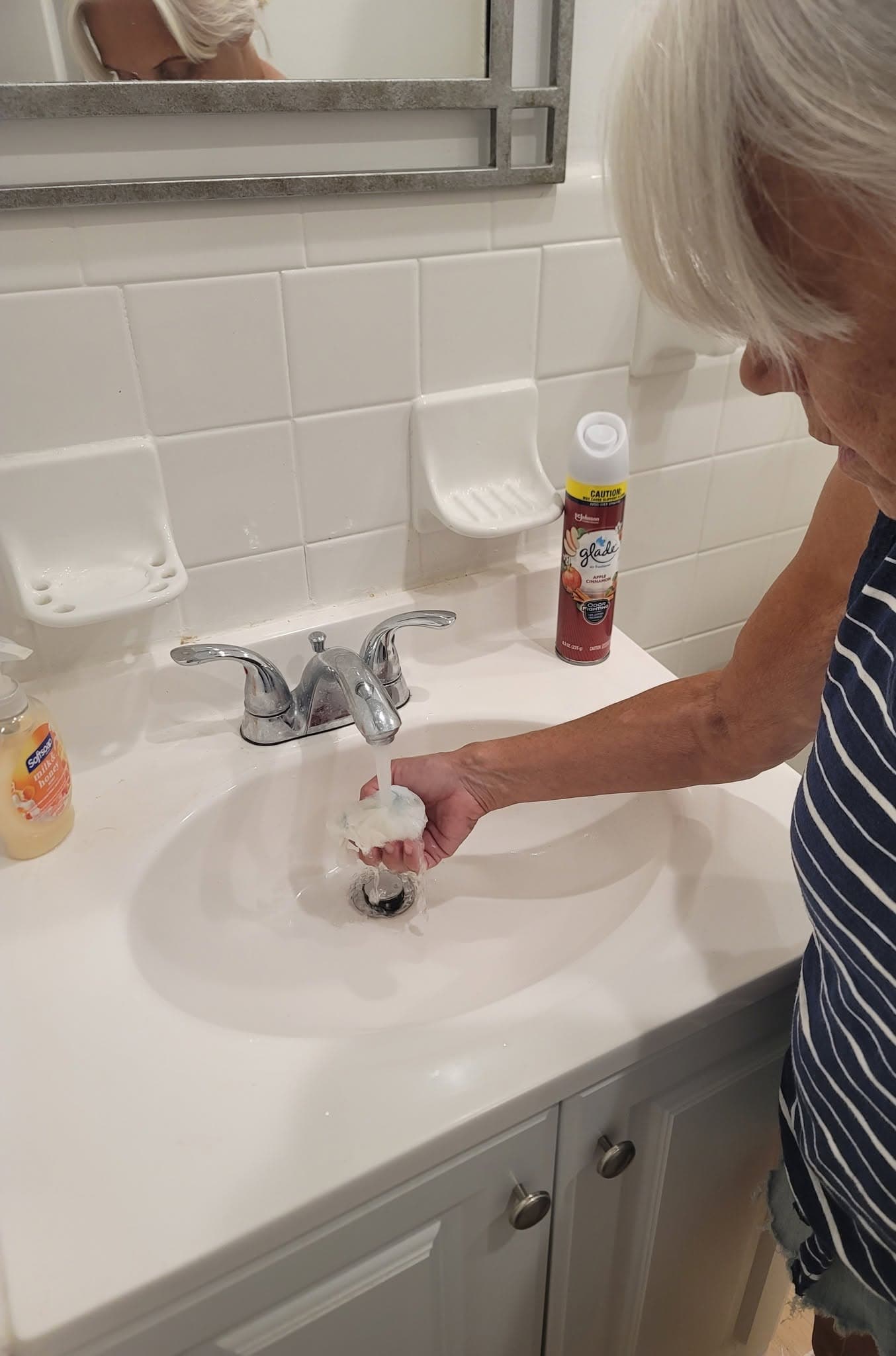 Cleaner rinsing a sponge at a bathroom sink